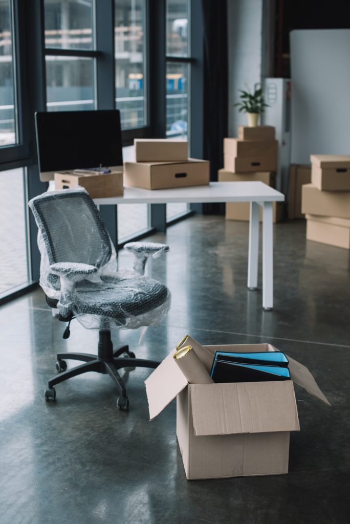 wrapped chair and cardboard boxes in office during relocation